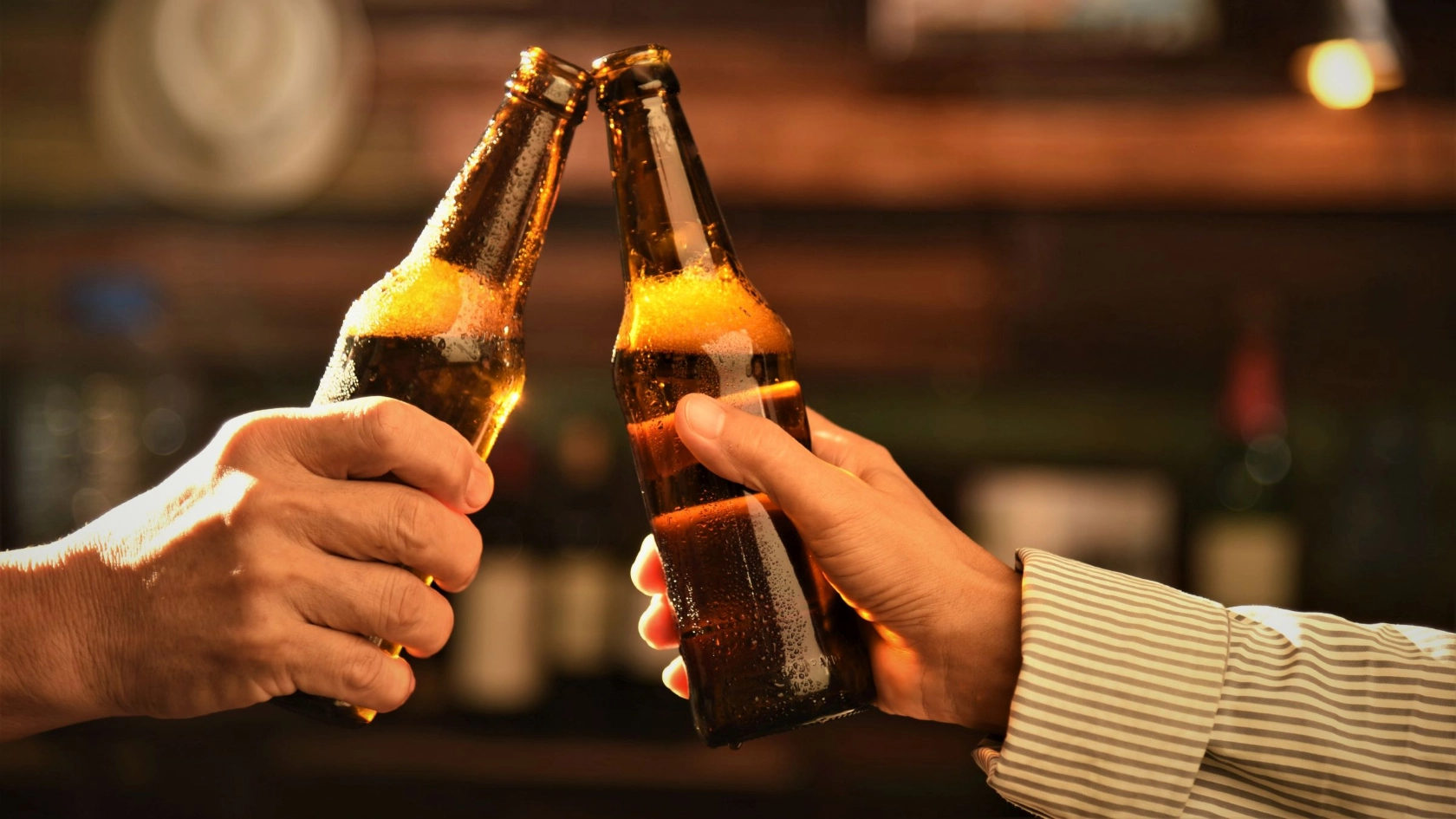 zwei Menschen stoßen mit zwei Flaschen Bier an