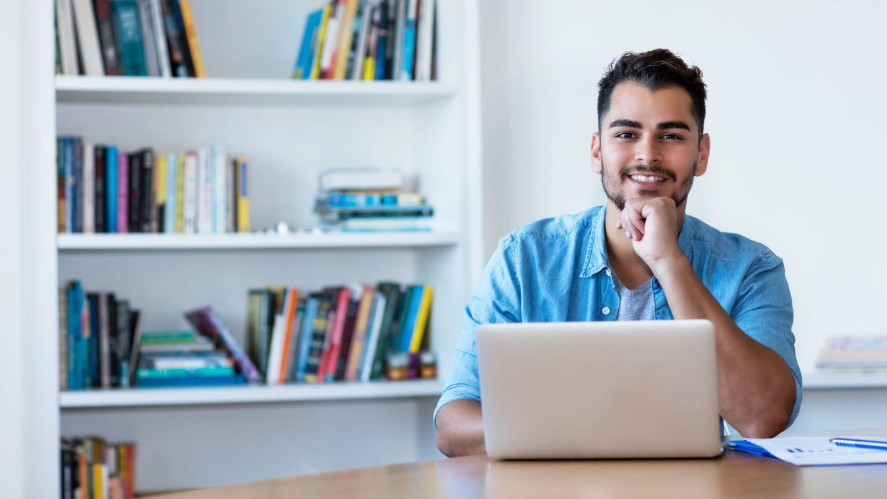 junger Mann sitzt mit einem Laptop zu Hause am Tisch