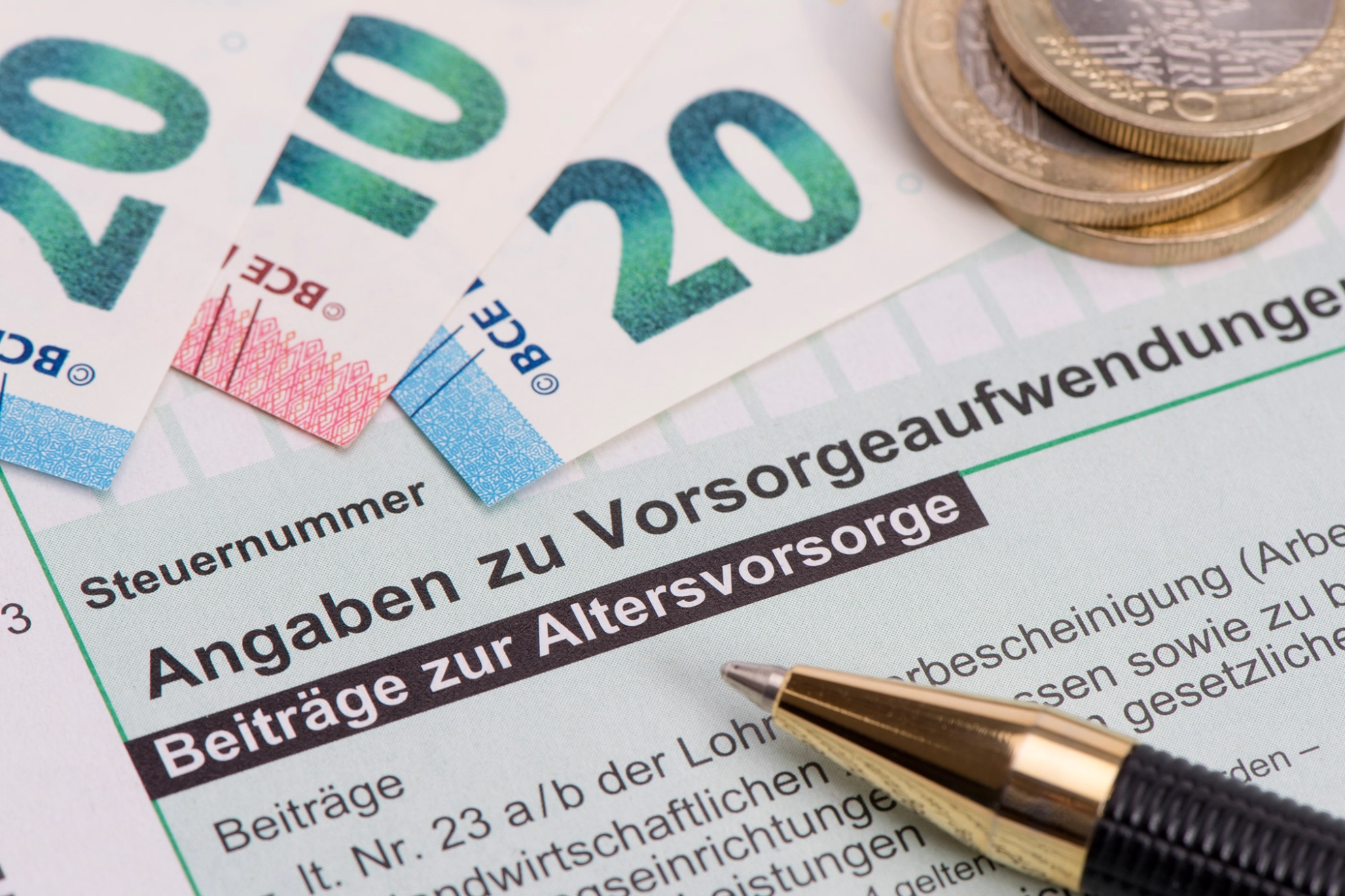 Geldscheine und Münzen liegen auf einem Formular zur Altervorsorge